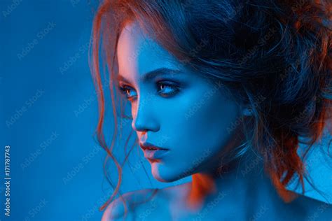 Portrait of beautiful girl in blue light and red light close up with ...