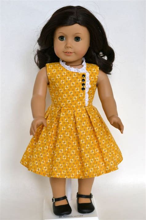 The Doll Is Wearing A Yellow Dress With White Flowers On It And Black