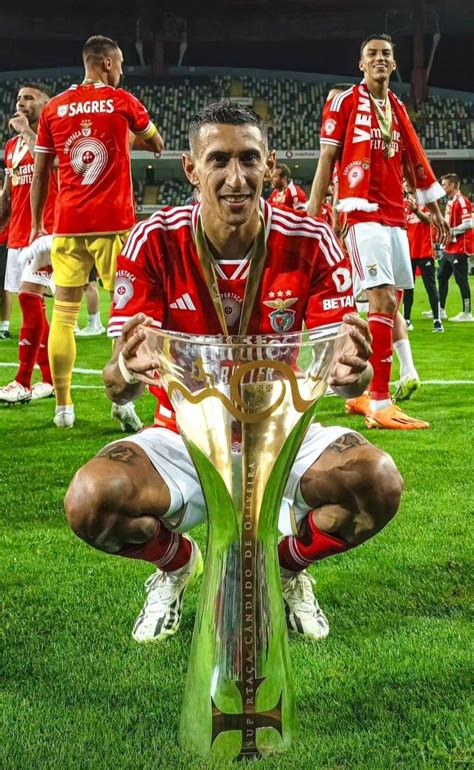 A Man Kneeling Down Next To A Trophy On Top Of A Soccer Field With