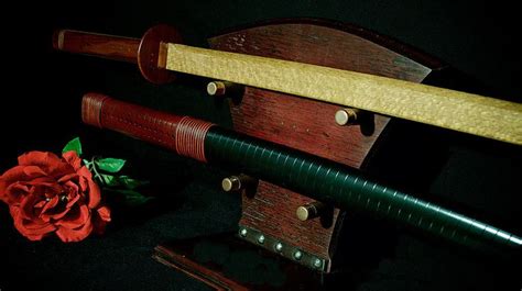 A Red Rose Sitting On Top Of A Wooden Bench Next To Two Swords And A Knife