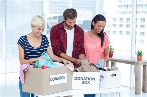 Premium Photo Smiling Young Friends Volunteers Separating Clothes