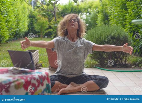 Mature Woman With Eyeglasses Performing Yoga Position With Tablet Meditation Outdoors In Green