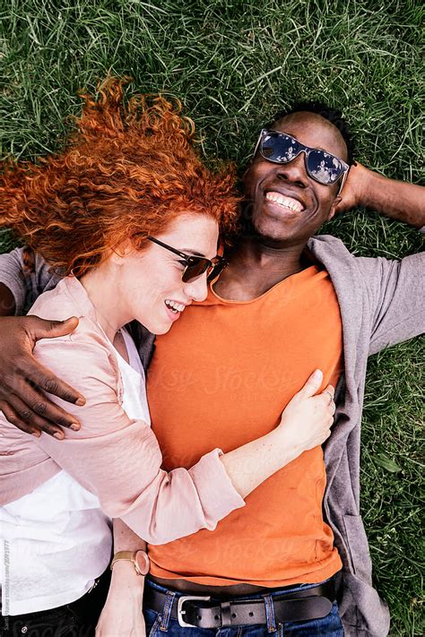 Embracing Diverse Couple Chilling On Grass By Stocksy Contributor