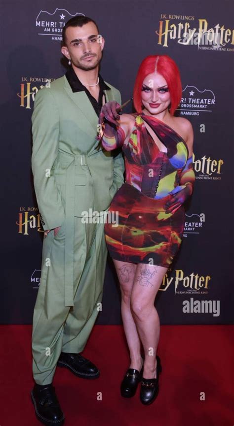 A Man And Woman Dressed In Costumes Posing For The Camera On A Red