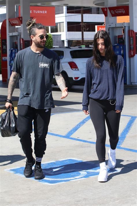 The Man And Woman Are Walking Down The Street Holding Hands While