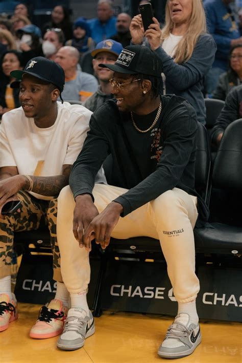 Two Men Sitting On The Sidelines At A Basketball Game One Is Holding A