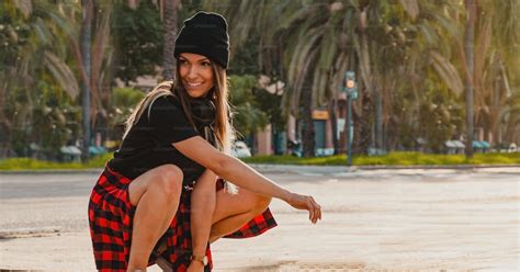 Une Jeune Femme Souriante Saccroupit En Faisant Du Skateboard Dans La