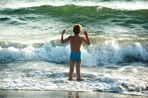 Premium Photo Rear View Of Shirtless Boy Standing On Shore At Beach