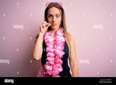 Jeune femme blonde portant un maillot de bain et des lei hawaïens floraux sur fond rose bouche