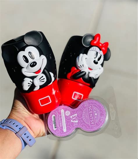 A Person Holding Two Mickey Mouse Toothbrushes In Their Hand