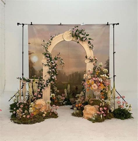 An Archway Decorated With Flowers And Greenery In Front Of A Painting