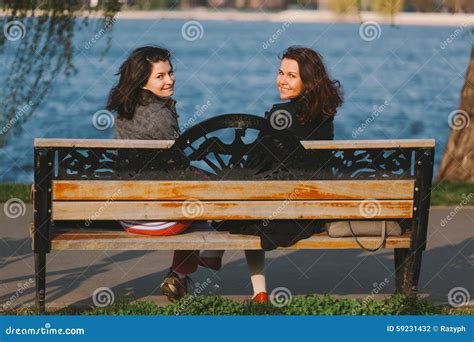 Filles Mignonnes S Asseyant Sur Un Banc En Bois Souriant Photo Stock