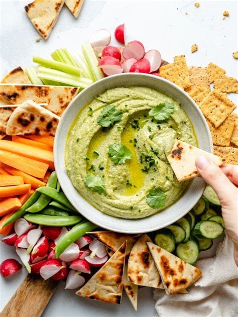 A Bowl Of Hummus Surrounded By Vegetables And Crackers