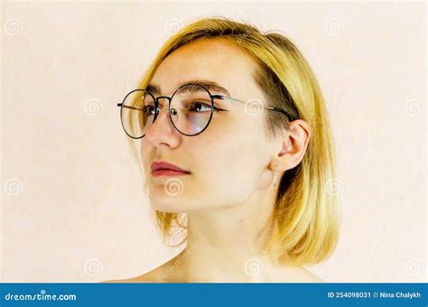 Portrait Of An Attractive Smiling Young Blonde Woman In Round Glasses