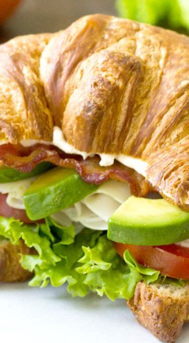 A Croissant Sandwich With Bacon Lettuce And Tomato Slices On It