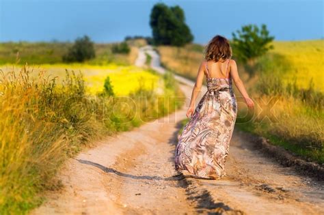 Beautiful White Girl Walking The Road Before Sunset Stock Photo