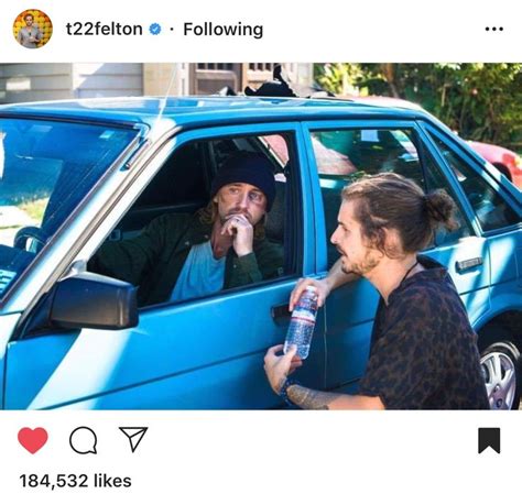 Two People Sitting In A Blue Car And One Is Holding A Water Bottle To