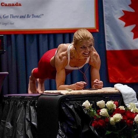 A Woman Is Doing Push Ups On Top Of A Table In Front Of A Canadian Flag