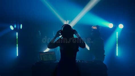 Female Dj Leading The Party At Nightclub With Crowd In Silhouette Stock