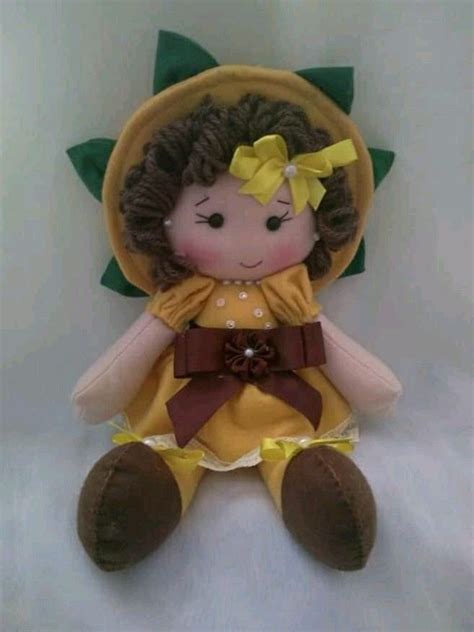 A Small Stuffed Doll With A Yellow Dress And Brown Hat On It S Head