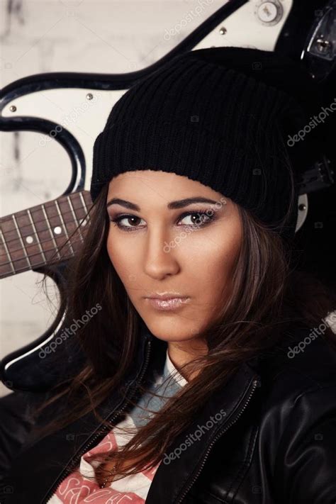 Retrato de una joven hermosa mujer músico sosteniendo su guitarra en su