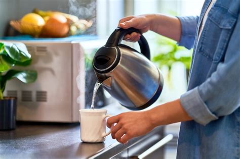 Premium Photo Female Hands Pouring Boiling Water From A Modern Metal