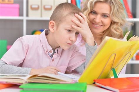 Portrait Of Mother With Her Son Doing Homework At Home Stock Photo