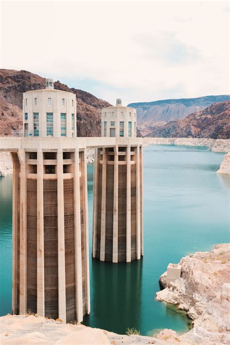 Brown And White Concrete Building Near Body Of Water During Daytime Photo Free Dam Image On