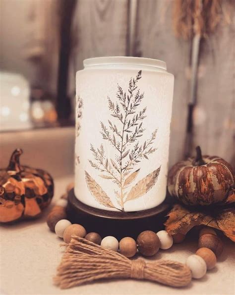 A White Candle Surrounded By Wooden Beads And Pumpkins On A Table With