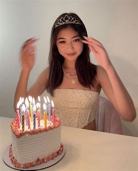 A Young Woman Wearing A Tiara Standing In Front Of A Birthday Cake With Lit Candles