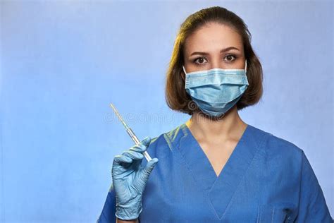 Doctor In Protective Mask And Blue Latex Gloves With Syringe With A