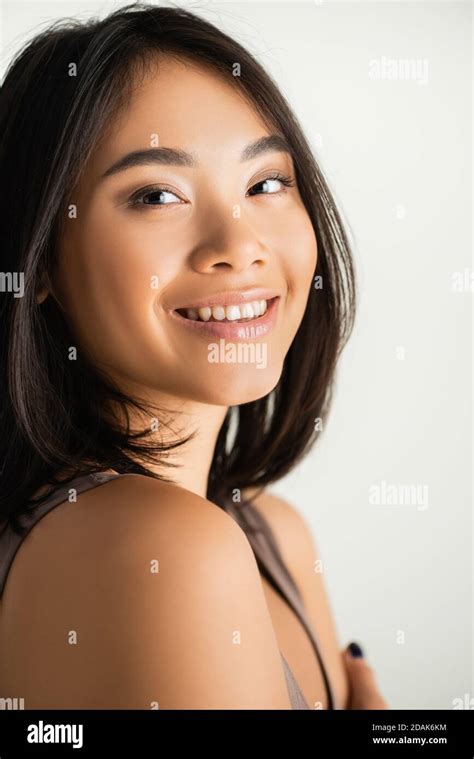 Brunette Asian Woman Smiling While Looking At Camera Isolated On White Stock Photo Alamy