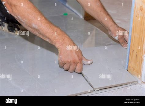 With The Help Of A Home Construction Worker Placing Ceramic Tile On An