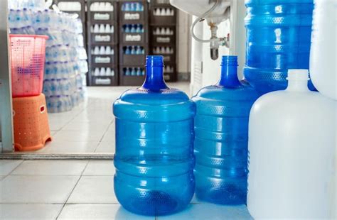 Botellas De Plástico Blancas Y Galones Azules De Agua Potable Se Apilan