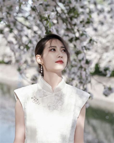 A Woman Standing In Front Of A Tree With White Flowers