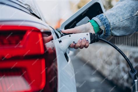 充電ピストルで電気自動車を充電している女性 無料の写真