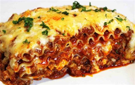 A White Plate Topped With Lasagna Covered In Sauce And Cheese On Top Of It