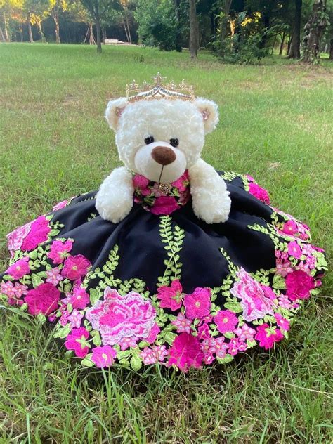 A White Teddy Bear Wearing A Black And Pink Dress With Flowers On It S