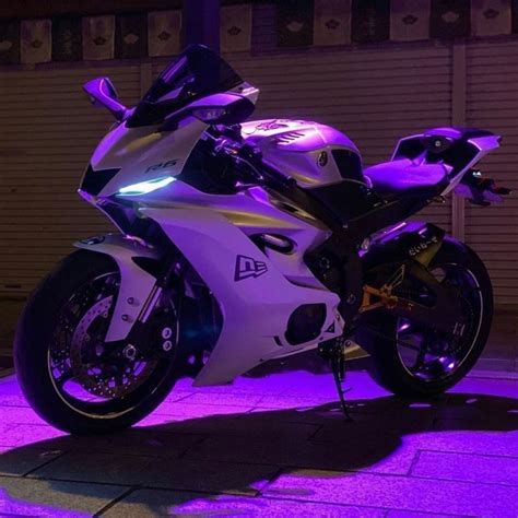 A White And Black Motorcycle Parked In Front Of A Building With Purple