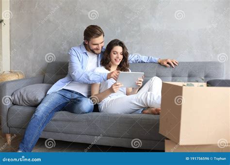 Happy Couple Sitting And Planning New Home Decoration At Home With A Tablet At Moving Day Stock