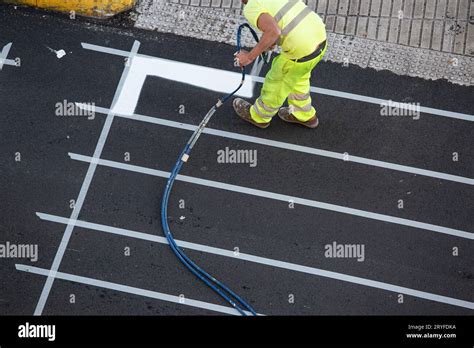 Worker Painting A Pedestrian Crosswalk Road Using Paint Sprayer Gun