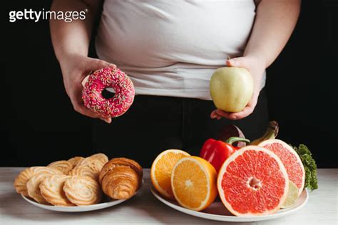 Fat Woman Choosing Between Healthy And Junk Food 이미지 1301424985 게티이미지뱅크