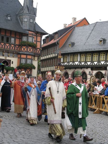 Several People Dressed In Costumes Walking Down A Cobblestone Street