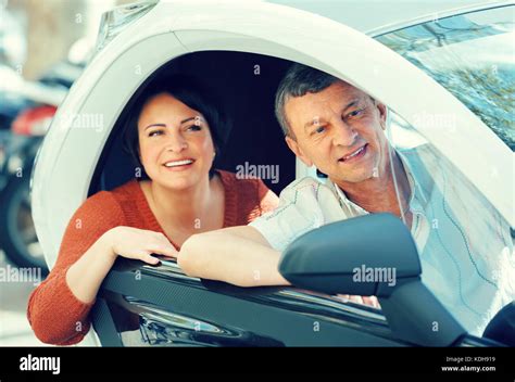Joyful Smiling Mature Couple Driving Twizy Electric Outside At Summer