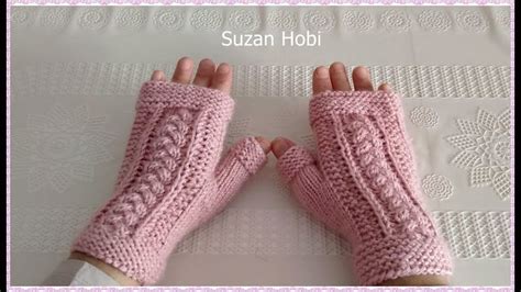 Two Hands Wearing Pink Knitted Mitts On Top Of A White Tablecloth With