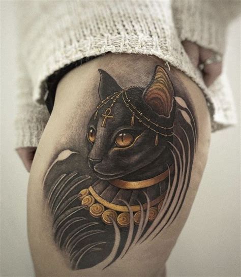 An Egyptian Cat Tattoo On The Back Of A Woman S Thigh With Gold Accents