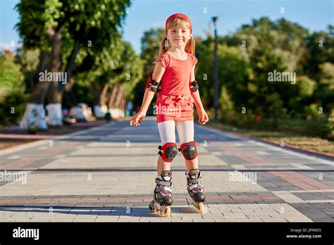 Pretty Little Girl Learning To Roller Skate Outdoors On Beautiful