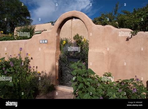 House With Adobe Low Wall With Arched Front Gate In Pueblo Revival