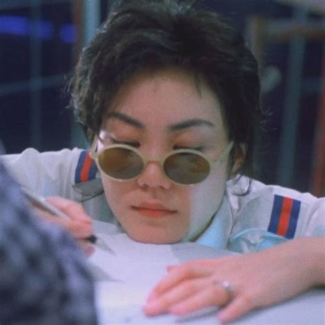 A Woman Wearing Sunglasses And Writing On A Piece Of Paper