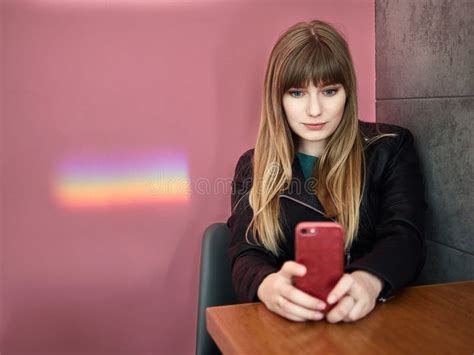 Portrait Of A Happy Blonde Long Haired Woman Posing On A Pink Background Sitting Against The